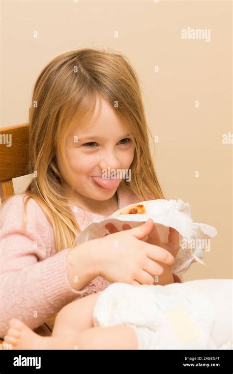 young preschool girl pulling a face, pretending to change doll's dirty ...