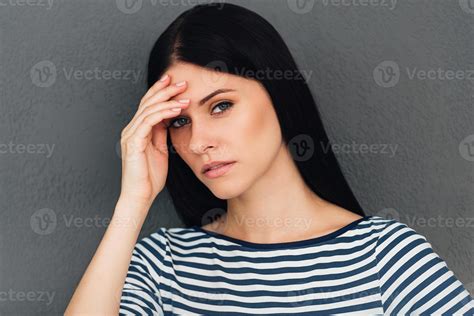 Feeling so tired. Frustrated young woman touching her head and looking