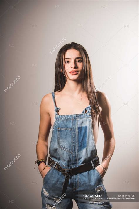 Brünettes Oben-ohne-Mädchen posiert in Jeans und blickt in die Kamera