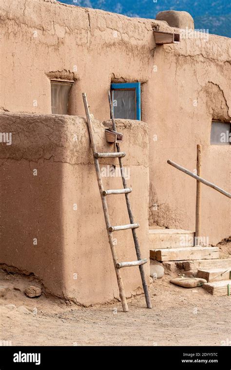 A handmade wooden ladder leaning against an adobe mud wall, in the ...