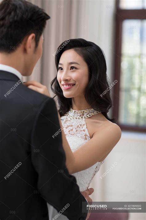 Young Chinese wife adjusting bow tie for her husband — Chinese