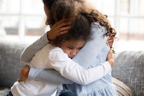Black mother and daughter embracing sitting on couch - Christian Leader