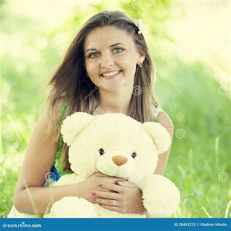 Beautiful Teen Girl with Teddy Bear in the Park at Green Grass. Stock