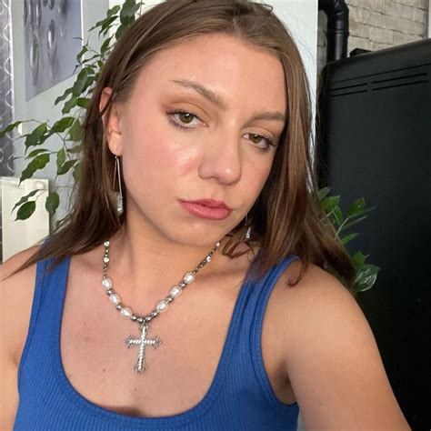 a woman wearing a blue tank top with a cross necklace on her neck ...