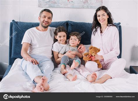 Cheerful Family Barefoot Sitting Bed Smiling While Looking Camera — Stock Photo © IgorVetushko ...