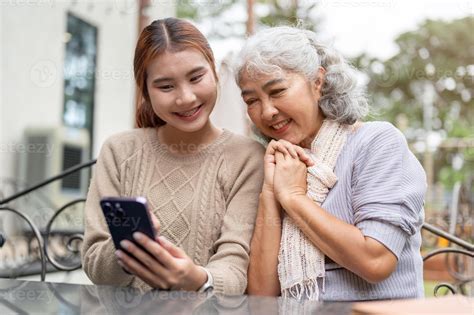 A lovely Asian granddaughter teaching her grandma using a modern