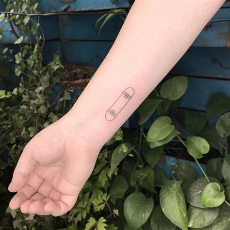 Fine line skateboard tattoo on the wrist.