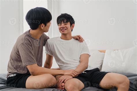 Handsome Asian gay couple talking on bed at home. Young Asian LGBTQ guy
