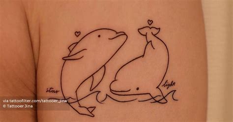 Fine line dolphin tattoo on the upper arm