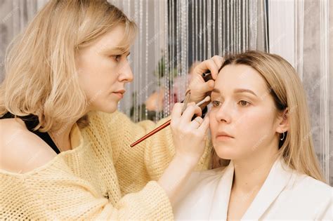 Premium Photo | A makeup artist girl makes up a model shooting in a ...