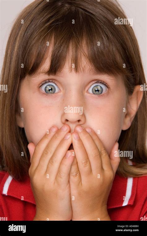 Tight cropped face of a scared young girl with hands covering mouth ...