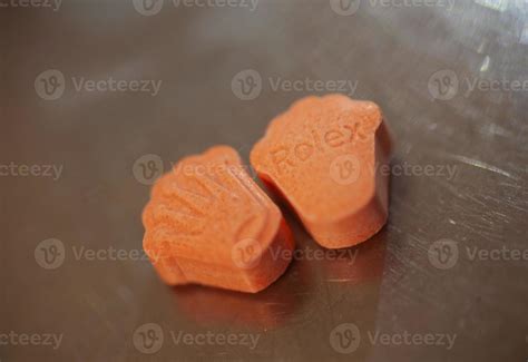 Orange pills with mdma ecstasy dope rolex drug close up background fine