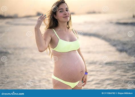 Portrait of Beautiful Pregnant Woman in Bikini Posing on the Beach at