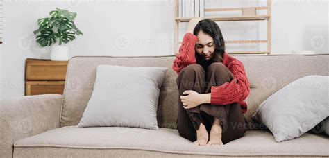 Depressed lonely unhappy mental woman sitting alone on the sofa at home