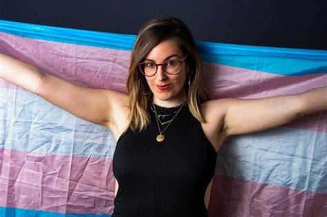 brunette haired transsexual woman  glasses  necklaces holding