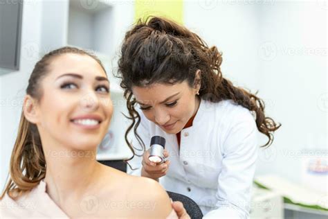 Female dermatologist carefully examining the skin of a female patient