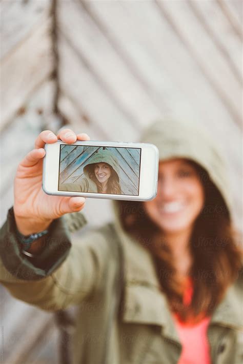 "Woman With Green Jacket Taking A Selfie With Mobile Camera" by Stocksy