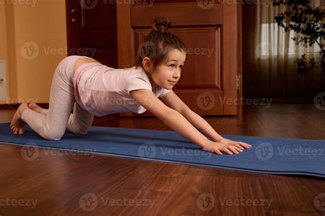 Side portrait of active sporty child girl stretching body and back on