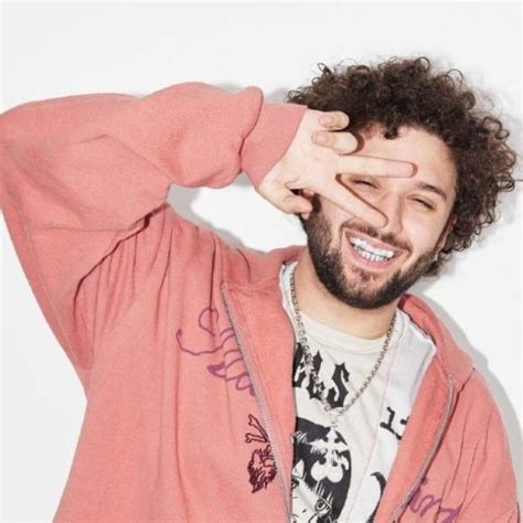 a man with curly hair is smiling and holding his hands to his face ...