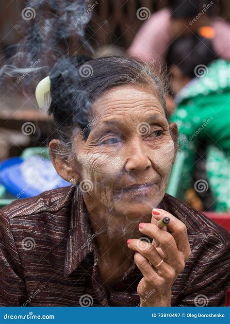 Older Lady Sitting on the Street Smoking a Cigarette. Yangon, Myanmar