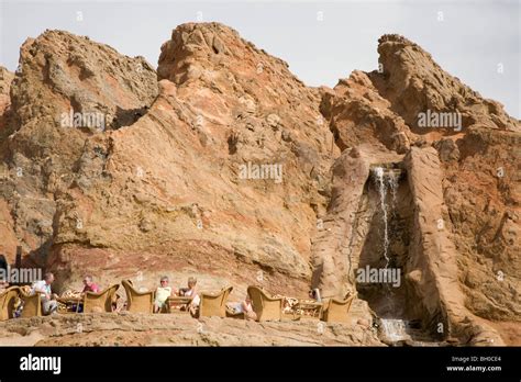 Tourists in terrace cafe by cliff rock face. Sharm El Sheikh market ...