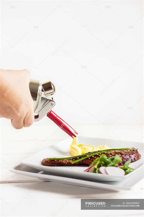 Squirting potato puree with a whipped cream dispenser on to a plate
