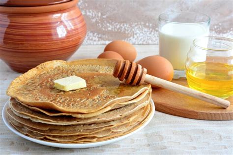 Premium Photo | Pile of russian blini on plate with honey, milk and ...