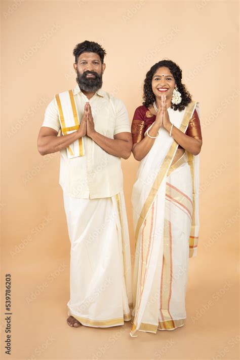 happy south indian couple wearing traditional white dress standing