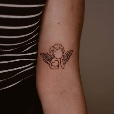Line art style cherub tattoo located on the bicep.