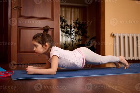 Little girl practicing yoga, doing push ups, press ups, four limbed