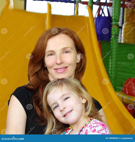 Daughter And Mother Together In Playground Slide Stock Photo