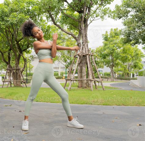 Young black woman stretching, exercising in nature park. Beautiful girl