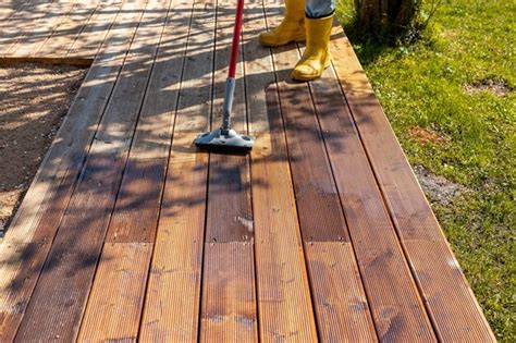 premium photo applying stain   wooden deck   brush   sunny day