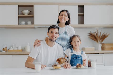 retrato familiar de feliz madre, hija y padre posan en la cocina