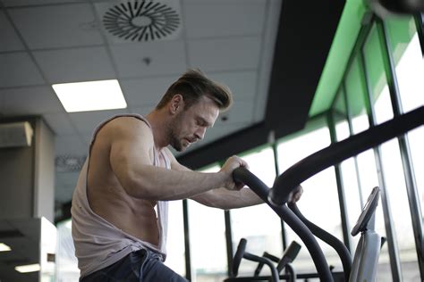 Strong sportsman using exercise bike during cardio workout in gym