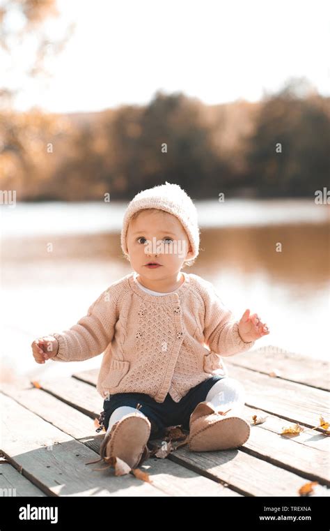 Cute baby girl 1 year old wearing stylish knitted clothes posing in autumn park outdoors ...