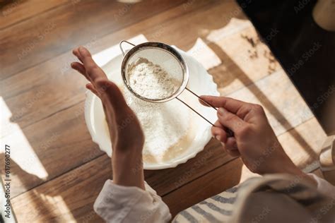 Sieving flour for cooking tasty and airy bread. Girl using sieve for ...