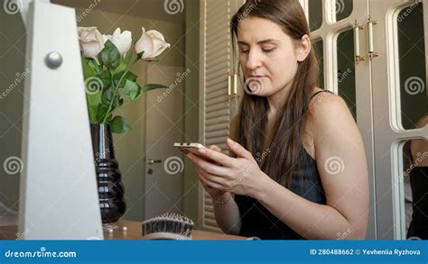 Young Brunette Woman Sitting at Makeup Table in Bedroom and Using ...