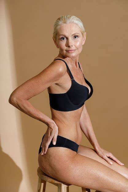 Studio shot of beautiful mature woman in black underwear looking at