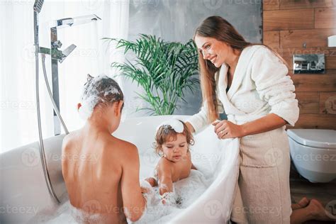 Having fun. Young mother helps her son and daughter. Two kids washing