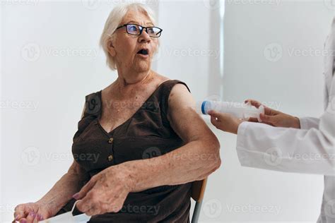 Nurse giving injection to an elderly woman with a syringe hospital