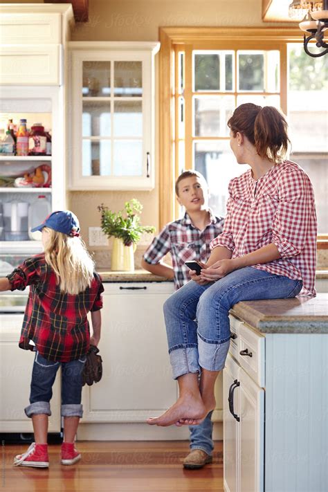 "Mom And Two Kids Hanging In Kitchen With Little Girl Looking In Fridge