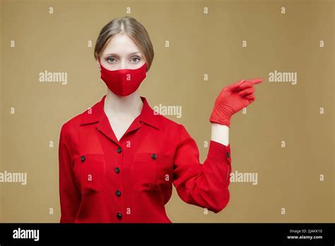 blonde woman in red gloves and a mask points the direction with her ...