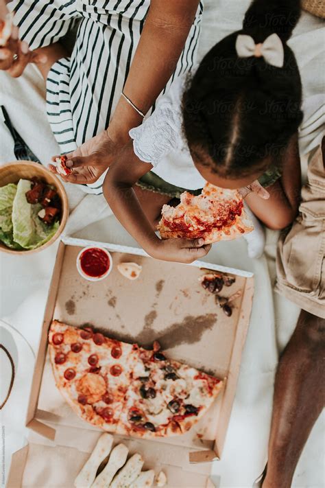 "A Family Of Three Having A Picnic In The Park & Eating Pizza" by