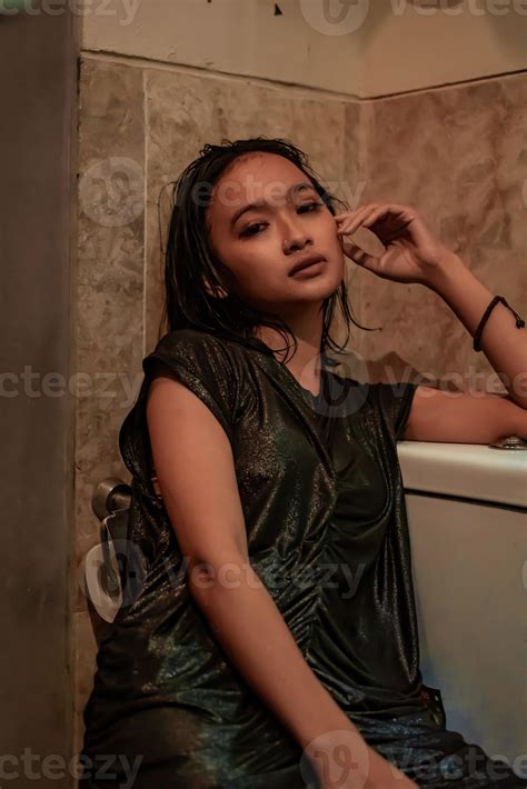 Hot and wet Asian girl poses with sensual style while wearing black wet