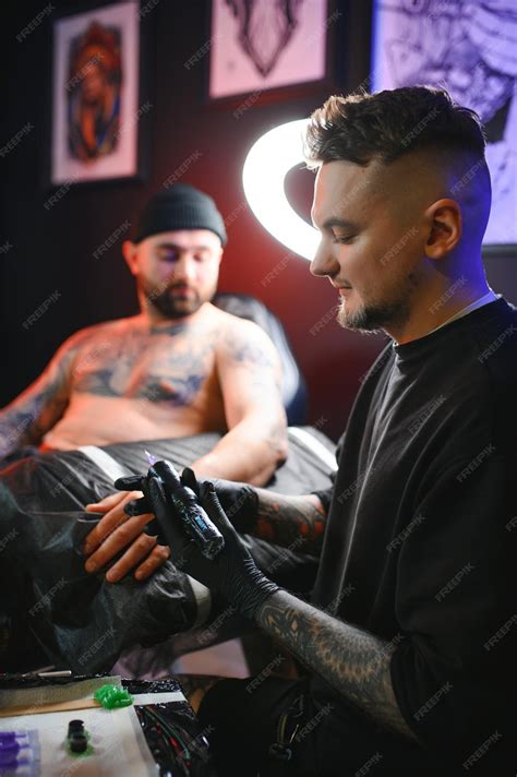 Premium Photo | Male tattoo artist holding a tattoo gun showing a