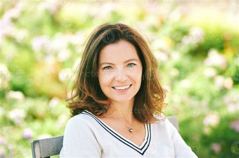 Outdoor portrait of beautiful 40 - 45 years old woman sitting on bench