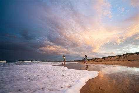 Travelers standing near foamy sea · Free Stock Photo