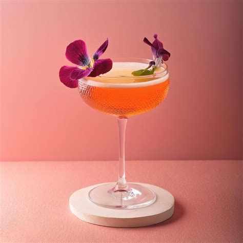 Cocktail with edible flower garnish, on pastel background 51444056