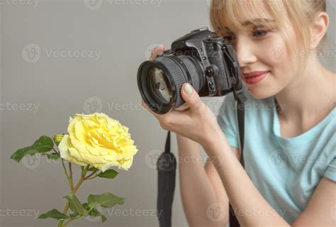 young woman photographer shooting a yellow rose with digital camera